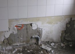 Gestripte badkamerwand tijdens de sloop, met het oude leidingwerk zichtbaar