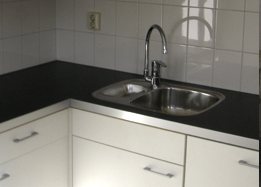 Keukenhoek met dubbele spoelbak en zwart werkblad na de renovatie