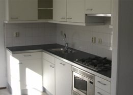 Gerenoveerde witte keuken met zwart werkblad, inbouwoven en gaskookplaat